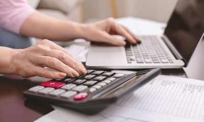 Mulher fazendo conta com calculadora e notebook, simulando a criação do IR