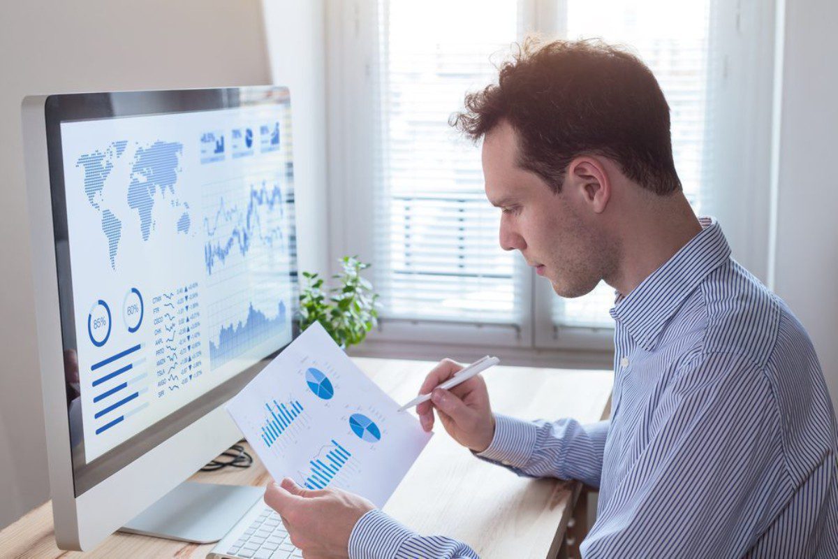 Homem Investidor acompanhando relatório com gráficos