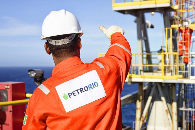 Funcionário da Prio dando um joia para outro funcionario em plataforma de petróleo