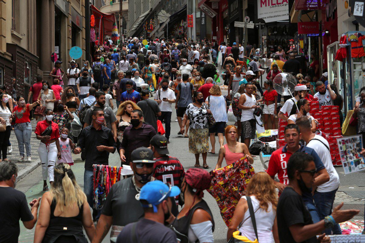 Pessoas caminham em rua de comércio popular em São Paulo