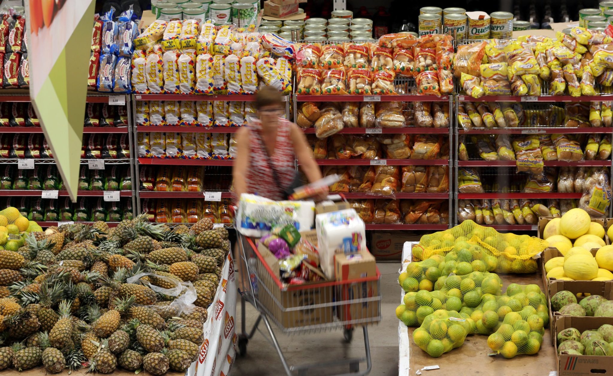 Mulher empurra um carrinho de compras em um supermercado, onde o preço dos produtos é impactado pelo IPCA.