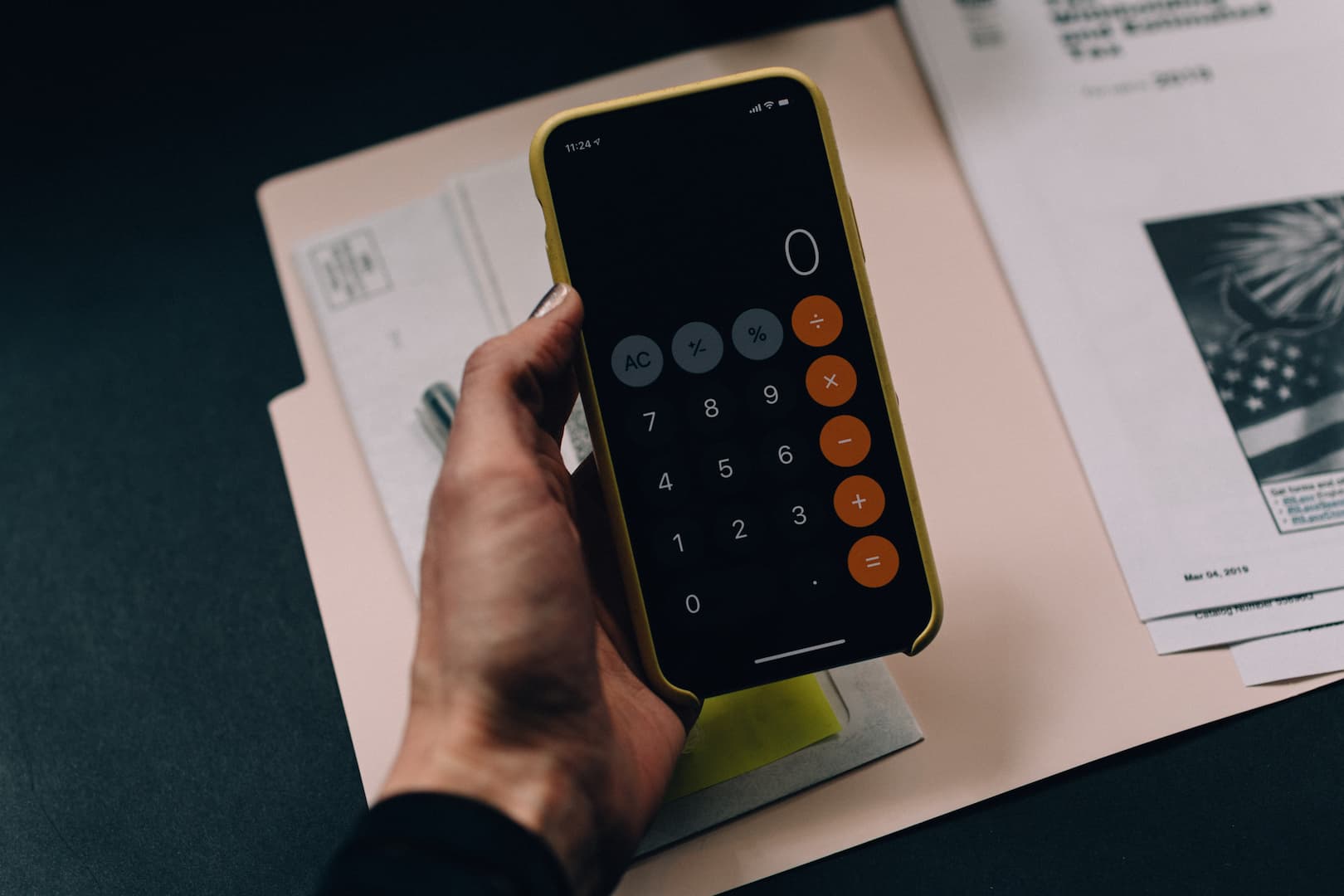 Uma mão segurando um celular aberto na tela da calculadora