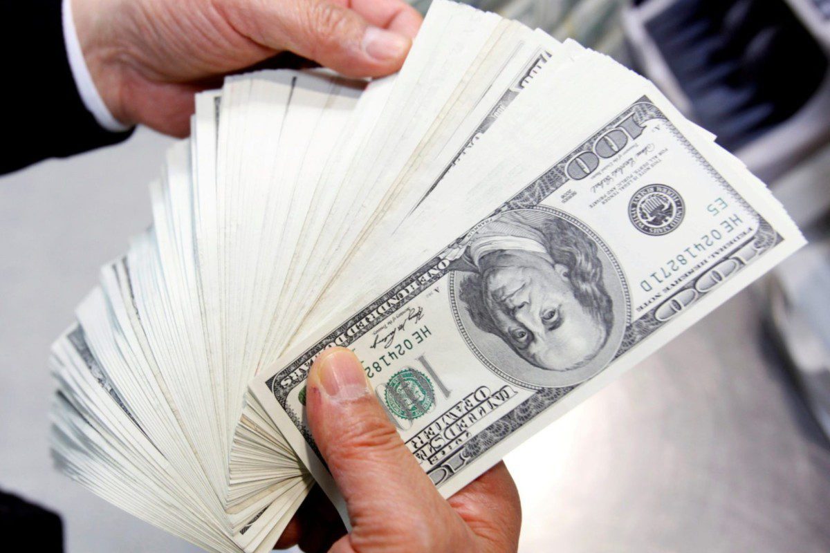 Mão de homem segurando notas de dólares