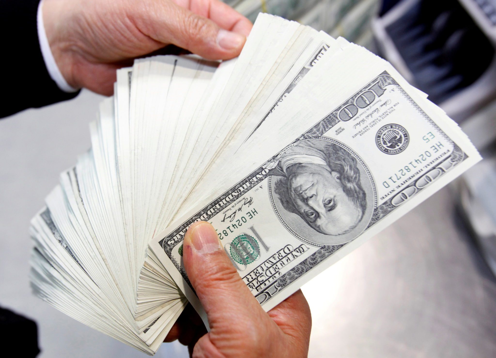 Mão de homem segurando notas de dólares