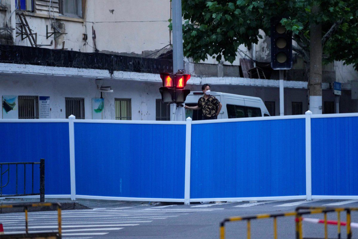 Homem observa sobre barreiras colocadas em rua durante lockdown para conter a disseminação da Covid-19 em Xangai, na China