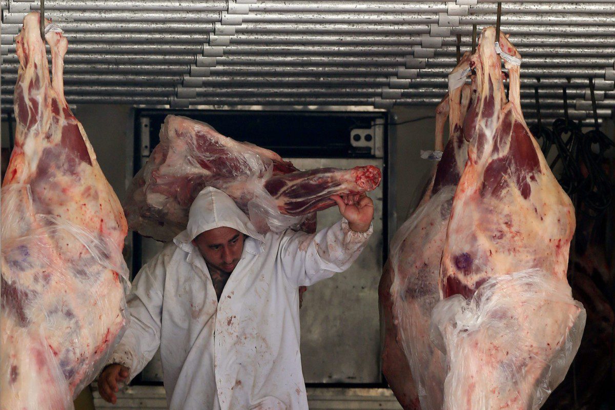 Trabalhador descarrega carne em açougue