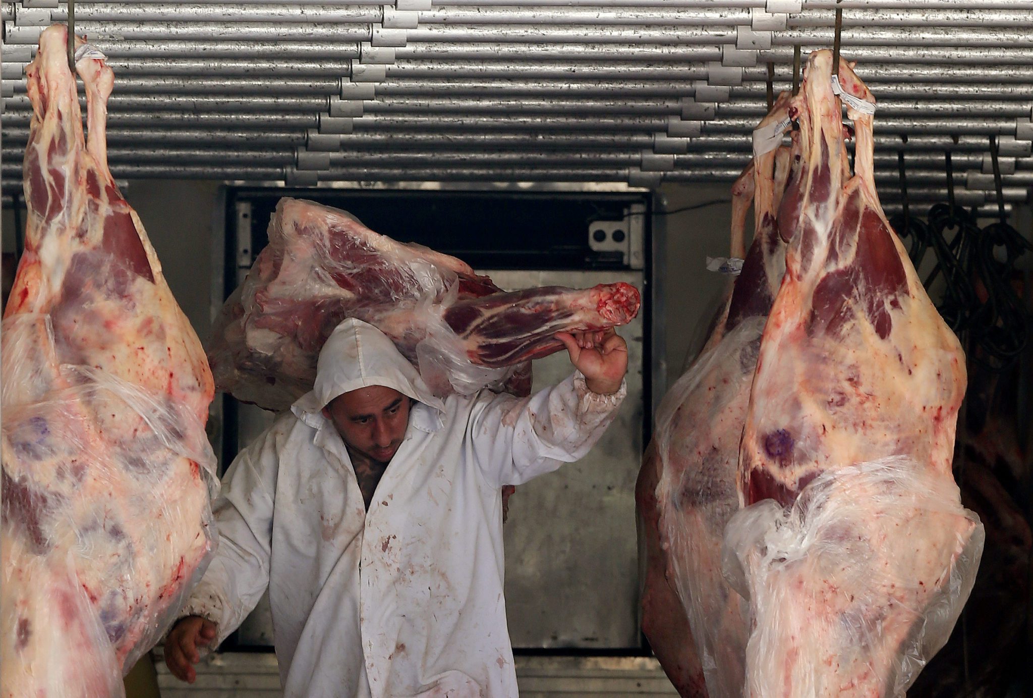 Trabalhador descarrega carne em açougue