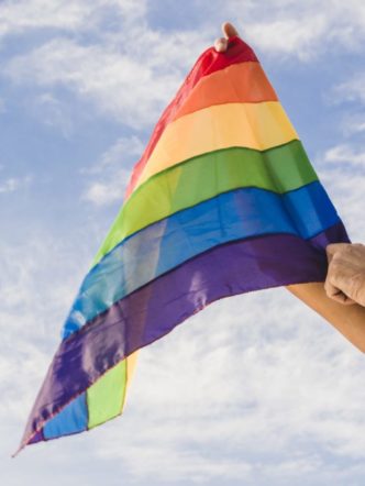 cropped-man-with-big-flag-in-lgbt-colors-and-blue-sky.jpg