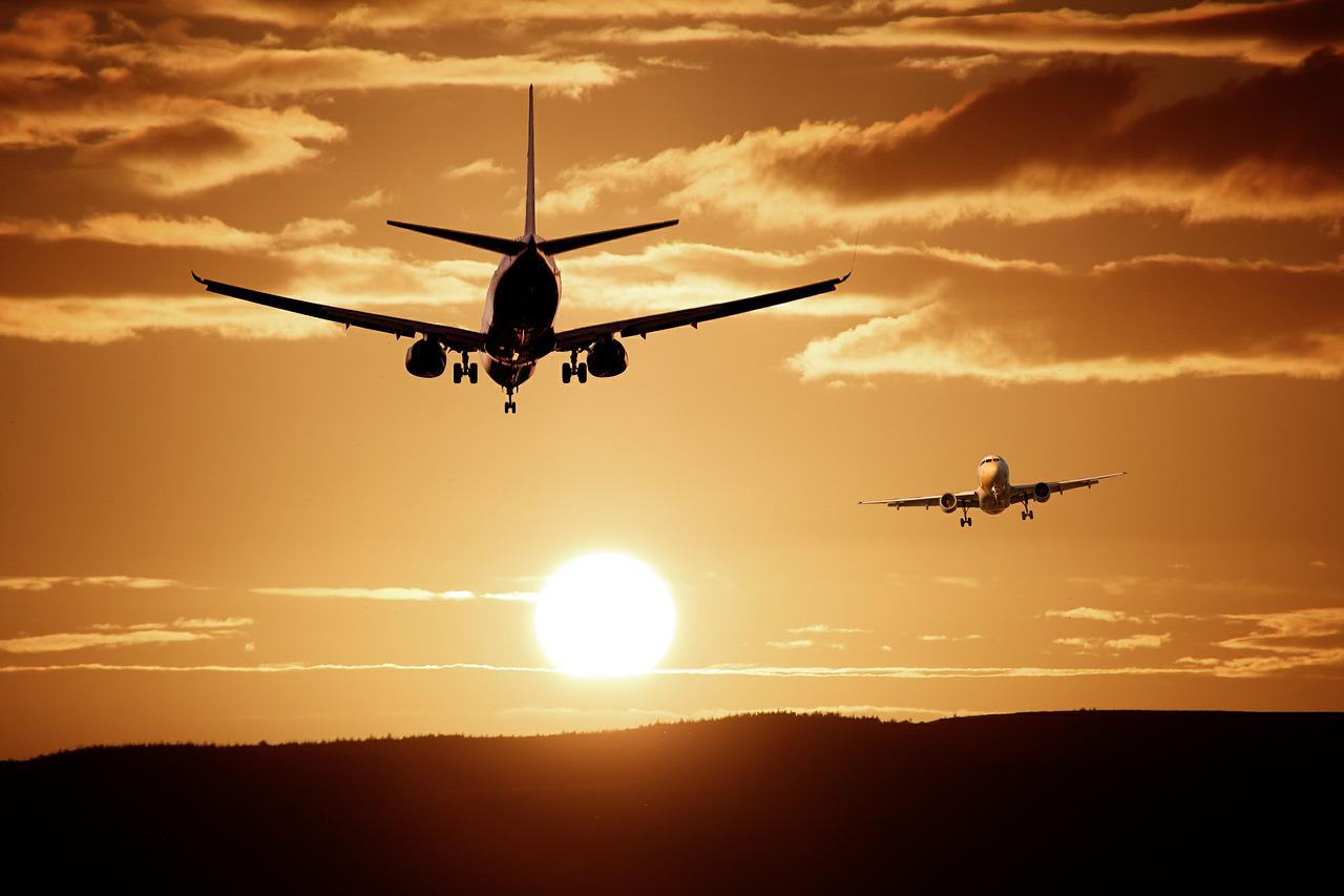 Dois aviões voando com o sol se pondo ao fundo, ilustrando o tema: dicas de viagem