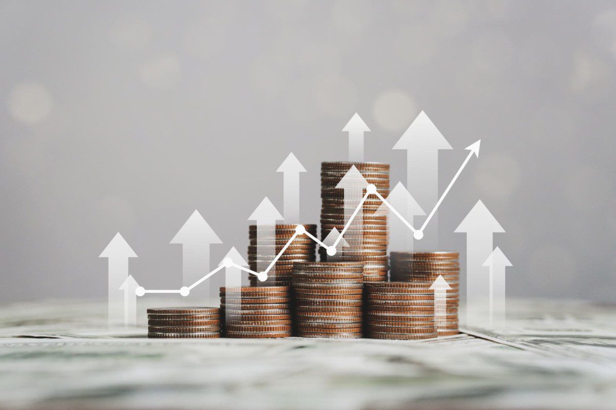 A imagem mostra várias pilhas de moedas com um gráfico de rentabilidade em crescimento, exemplificando os resultados da diversificação de investimentos, representando os investimentos em CDI. (Foto: Shutterstock / d.ee_angelo)