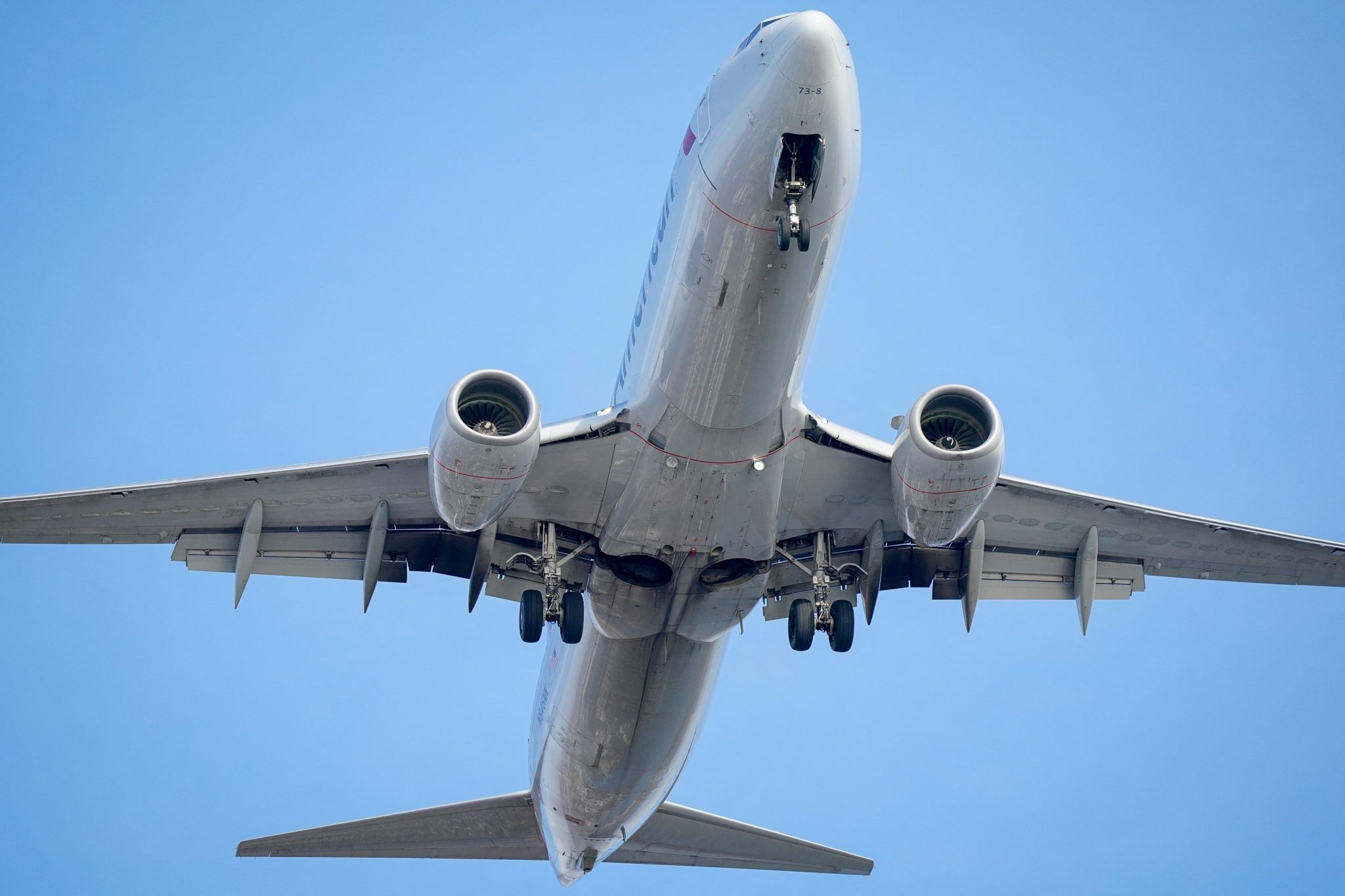 Avião sendo visto de baixo, com um céu azul atrás. Ilustrando o tema "dicas de viagem"