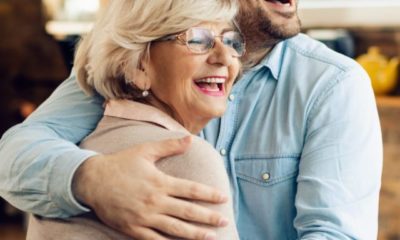 Cheerful man and his mature mother embracing in the kitchen.