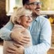 Cheerful man and his mature mother embracing in the kitchen.