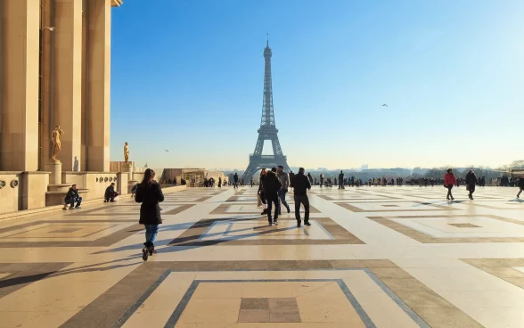 Turistas caminham pela Esplanada no Trocadéro, com vista para a Torre Eiffel em Paris, França