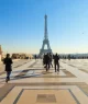 Turistas caminham pela Esplanada no Trocadéro, com vista para a Torre Eiffel em Paris, França