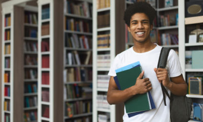 Jovem estudante segurando cadernos em uma biblioteca