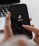 Pessoa manuseia um celular que exibe o logo do TikTok
