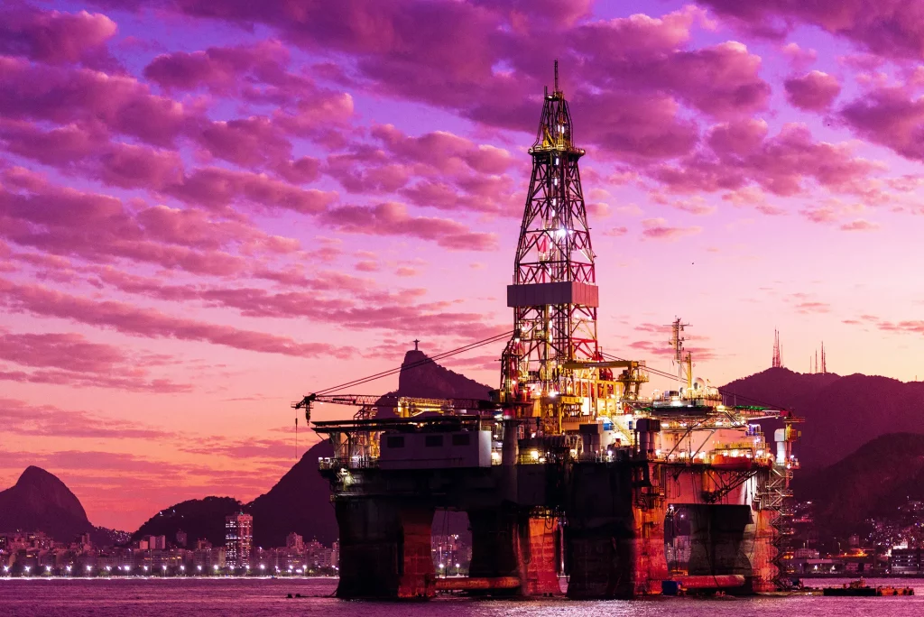 Silhueta de plataforma de perfuração de petróleo na Baía de Guanabara, no Rio de Janeiro, Brasil, com céu dramático ao pôr do sol