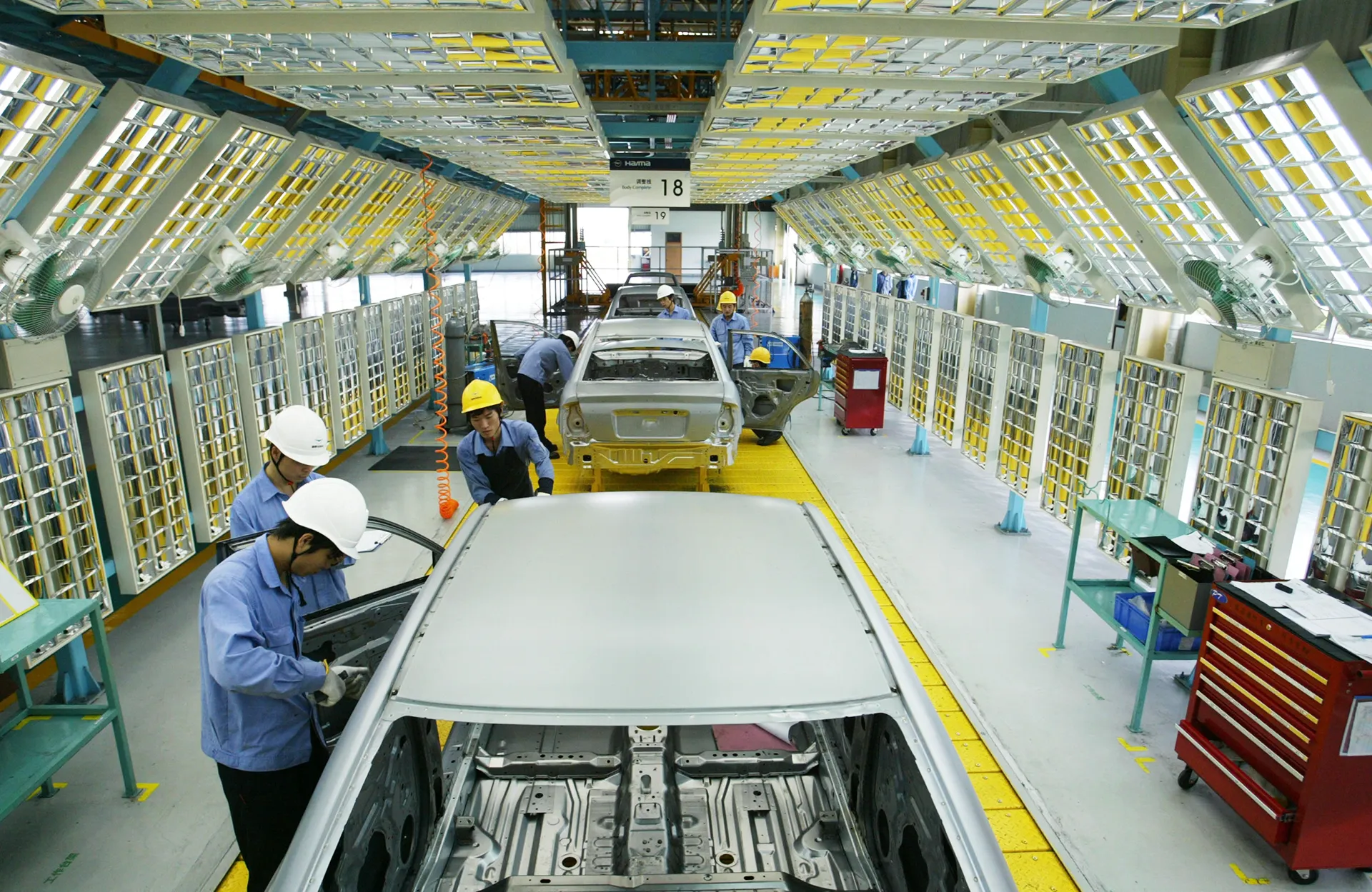 Funcionários montam carros da linha de veículos "Família" da Mazda no Grupo Haima Automobile Co., Ltd. da China First Automobile Works (FAW), em 6 de abril de 2005, em Haikou, província de Hainan, China.