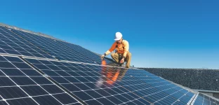 Técnico de painel solar com broca instalando painéis solares em um telhado
