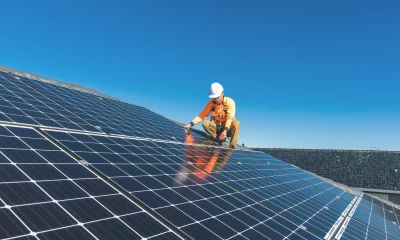 Técnico de painel solar com broca instalando painéis solares em um telhado