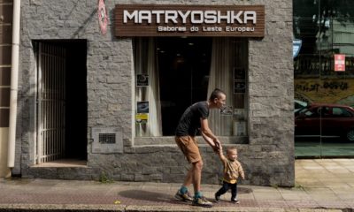 Grigorii Mikhailov e seu filho em frente a um restaurante que serve culinária da Europa Oriental, em Florianópolis, Brasil, no início deste ano.