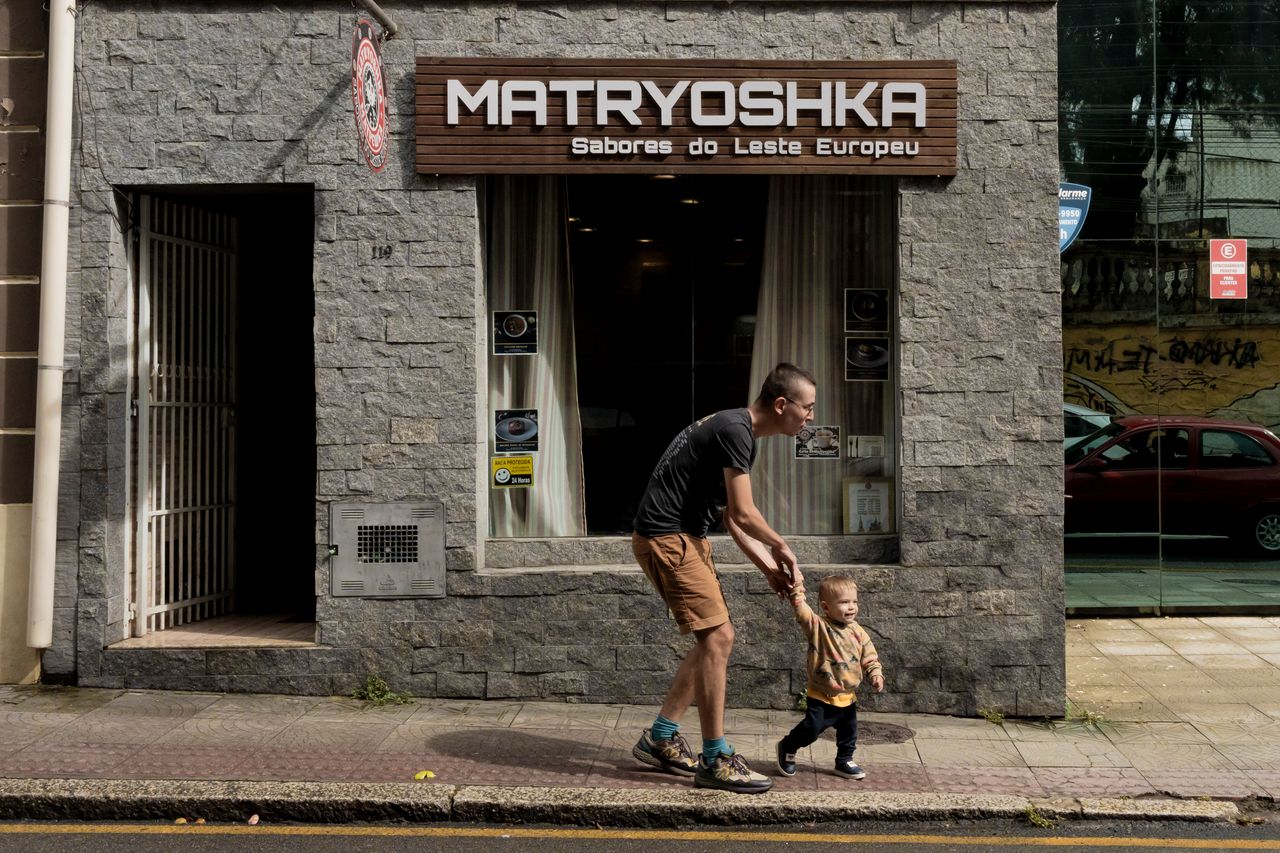 Grigorii Mikhailov e seu filho em frente a um restaurante que serve culinária da Europa Oriental, em Florianópolis, Brasil, no início deste ano.