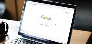 Um homem digitando no mecanismo de busca Google em um laptop