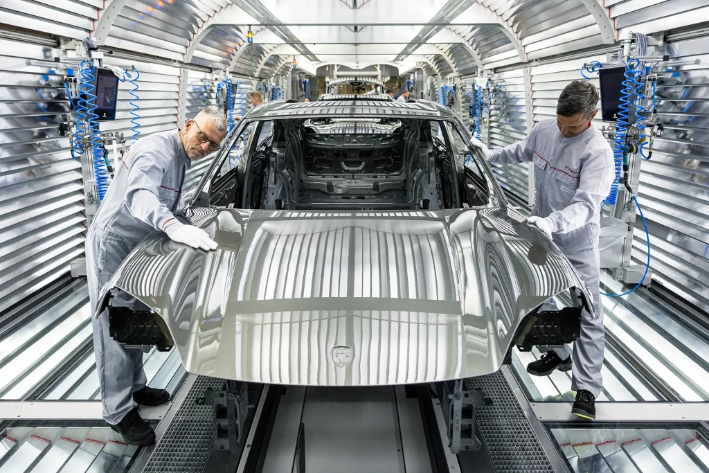 Trabalhadores montam o novo Porsche Macan totalmente elétrico na fábrica de montagem da Porsche em 6 de maio de 2024 em Leipzig, Alemanha. O Macan elétrico é o segundo carro elétrico da Porsche depois do Taycan. A empresa também oferece dois carros híbridos. (Foto: Jens Schlueter/Getty Images)