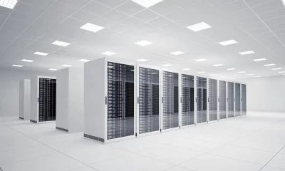 Data center moderno e bem organizado, com fileiras de racks de servidores sob iluminação intensa e espaço otimizado para alta tecnologia e eficiência.