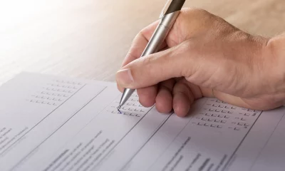 Mão com caneta anotando dados em um formulário em papel, em uma pesquisa