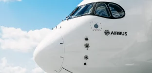 Parte frontal de uma aeronave da Airbus contra um céu azul com algumas nuvens esparsas, mostrando o nariz do avião, a cabine de comando com janelas curvas e o logotipo da Airbus na fuselagem branca.