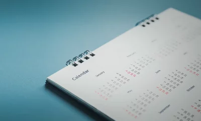 Um calendário de mesa espiral minimalista deitado sobre uma superfície plana com fundo azul.