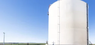 Vista do tanque de armazenamento de petróleo bruto e do oleoduto contra um céu azul.