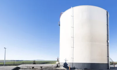 Vista do tanque de armazenamento de petróleo bruto e do oleoduto contra um céu azul.