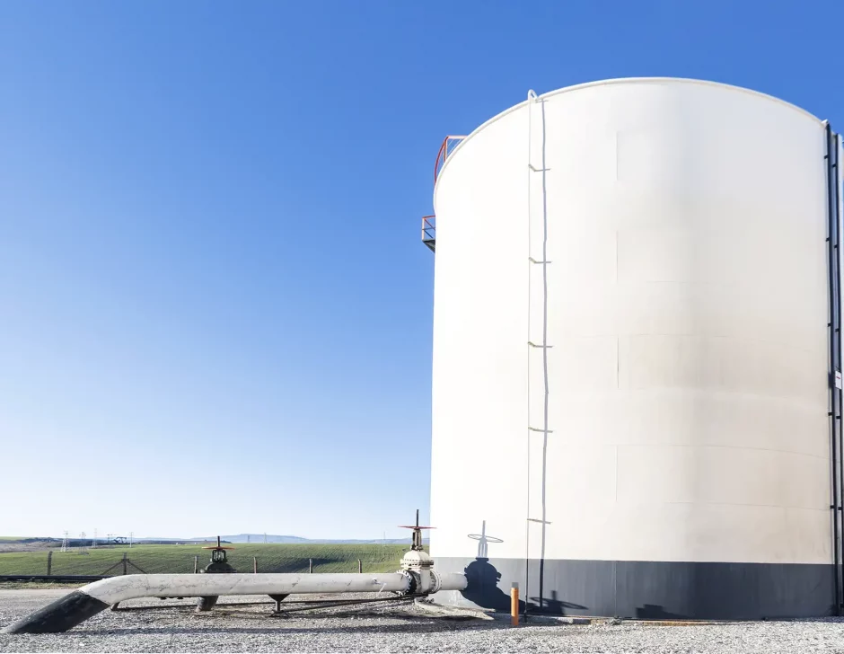 Vista do tanque de armazenamento de petróleo bruto e do oleoduto contra um céu azul.