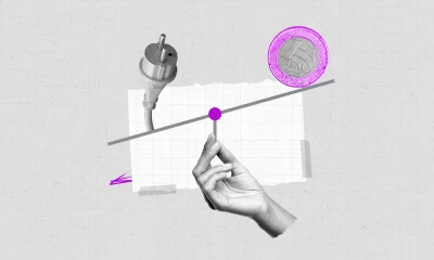 Colagem representando o preço da energia elétrica. Uma mão segura uma balança onde oscilam os pesos de uma tomada e de uma moeda de 1 real.