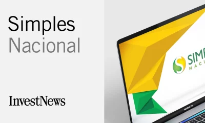 Imagem dividida em duas seções: à esquerda, fundo cinza claro com o texto "Simples Nacional" e "InvestNews"; à direita, tela de MacBook Pro mostrando gráficos geométricos em amarelo e verde e o logo do Simples Nacional.