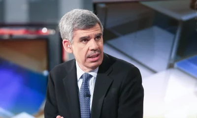 Foto de Mohamed El-Erian, conselheiro econômico, um homem de origem egípcia, com pele clara, cabelo e bigode grisalhos, usando um terno preto e gravata azul escuro durante entrevista em um programa de televisão.