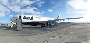 A imagem mostra um avião da companhia aérea Azul estacionado na pista de um aeroporto em um dia claro, com céu azul e algumas nuvens.