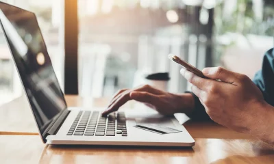 Mulher digitando em um notebook enquanto segura um cartão de crédito