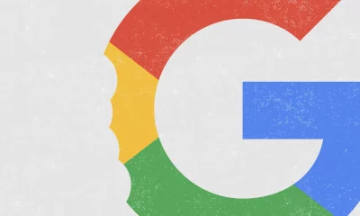 A imagem apresenta o logo estilizado da Google (com um desenho sugerindo uma "mordida"do lado esquerdo), com a letra "G" dividida em segmentos vermelhos, verdes, azuis e amarelos, sobre um fundo cinza claro com pequenas manchas brancas.