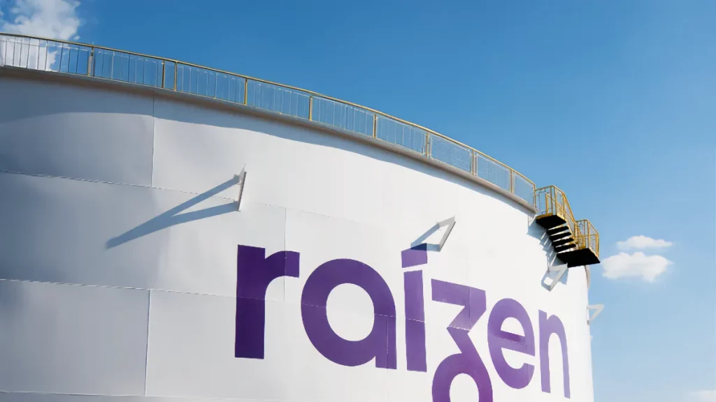 Tanque industrial branco com logotipo "raizen" em roxo, escada lateral e céu azul claro ao fundo.