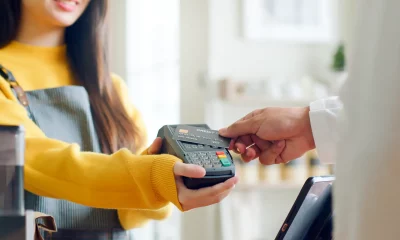 Imagem de uma pessoa segurando uma máquina de cartão em um ambiente comercial, prestes a realizar um pagamento.