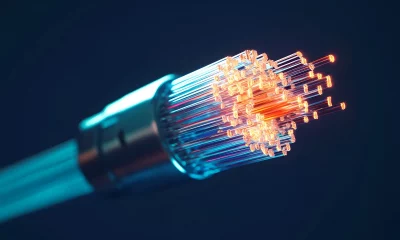 Um cabo de fibra óptica com fibras brilhantes em tons de laranja, vermelho e azul destaca-se contra um fundo escuro, transmitindo tecnologia avançada e comunicação.