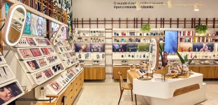 Imagem de uma loja da Natura, marca de cosméticos, moderna e bem iluminada com prateleiras cheias de produtos de maquiagem, perfumes e cosméticos para homens, e uma ilha central com design sofisticado.